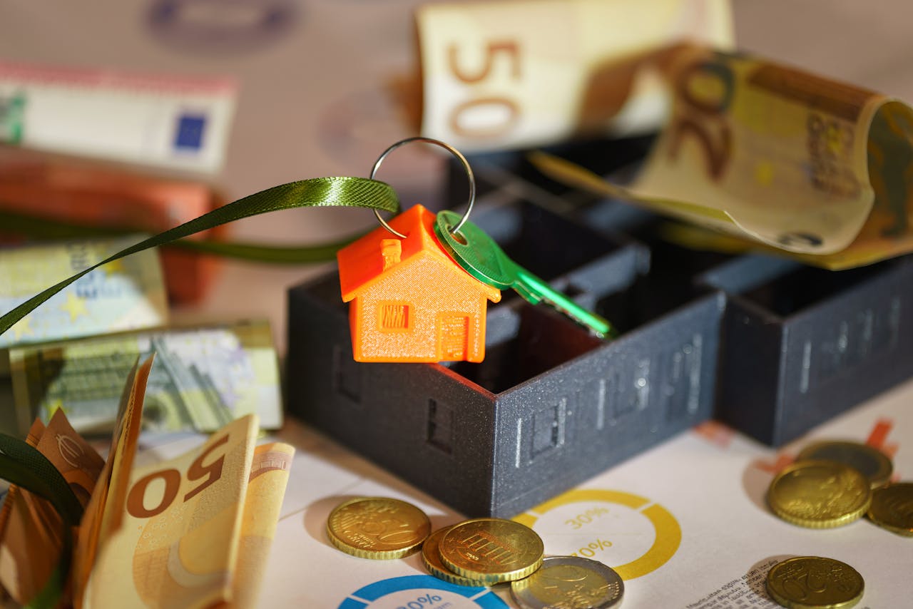Image depicting real estate investment with keychain, euros, and financial charts.